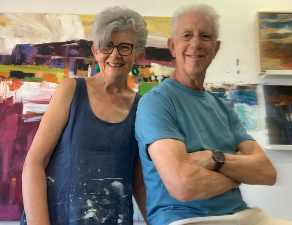 Two people standing in front of colorful abstract paintings