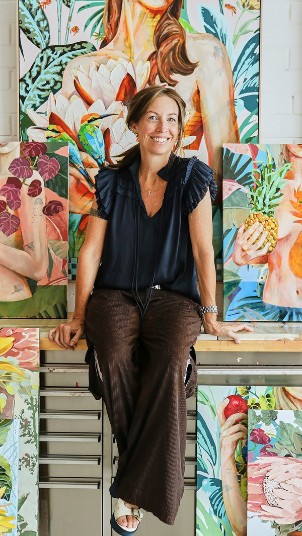 Jessica Watts sitting among colourful paintings of women and nature